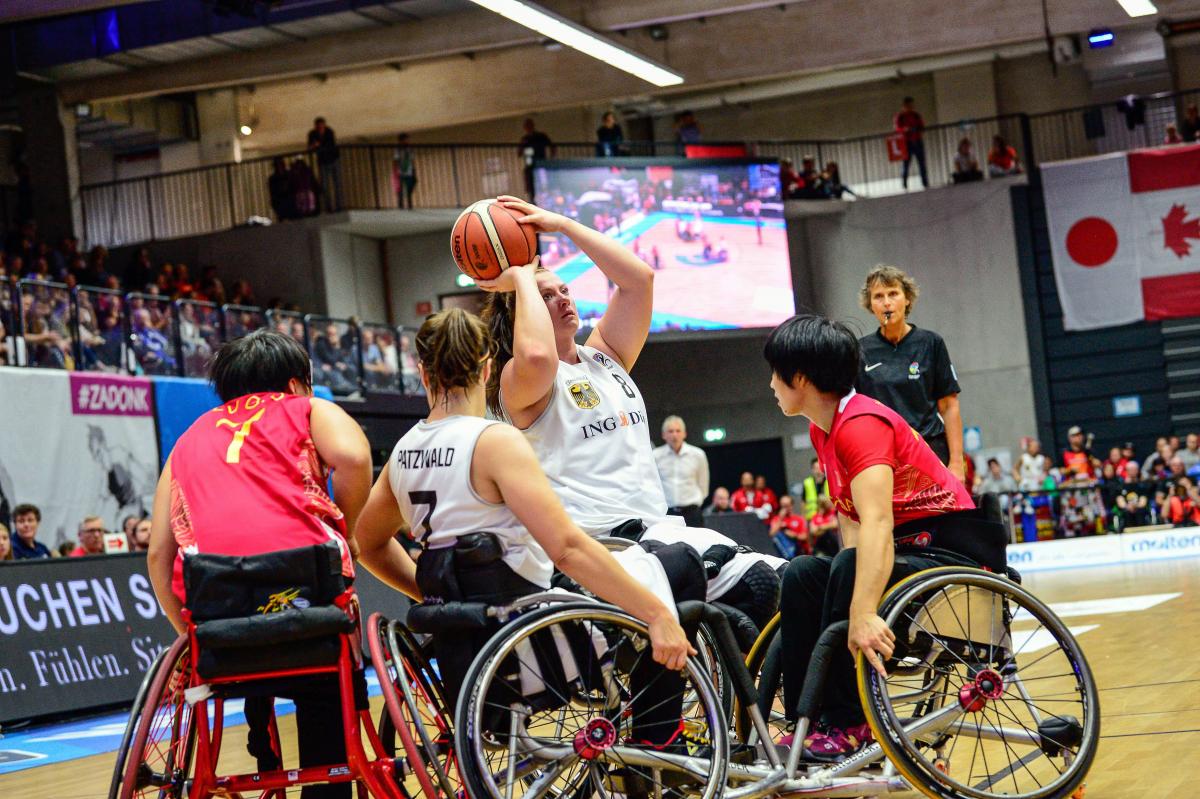 Woman shoots basketball over defenders