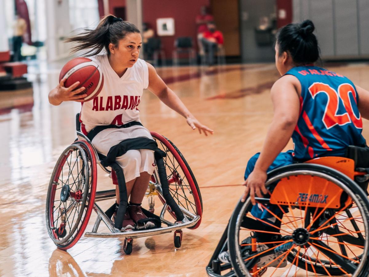 Woman playing wheelchair basketball tries to get around her defender