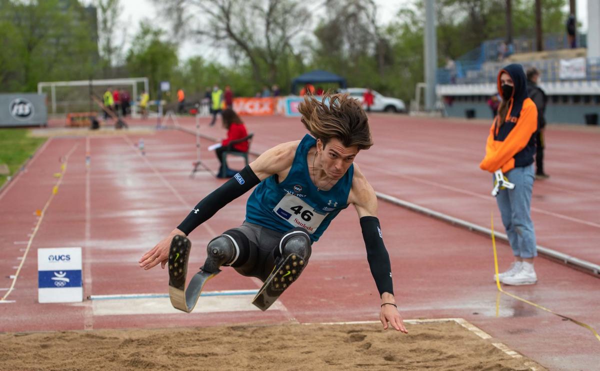 A men with prosthetic legs competing in a long jump event observed by a female official