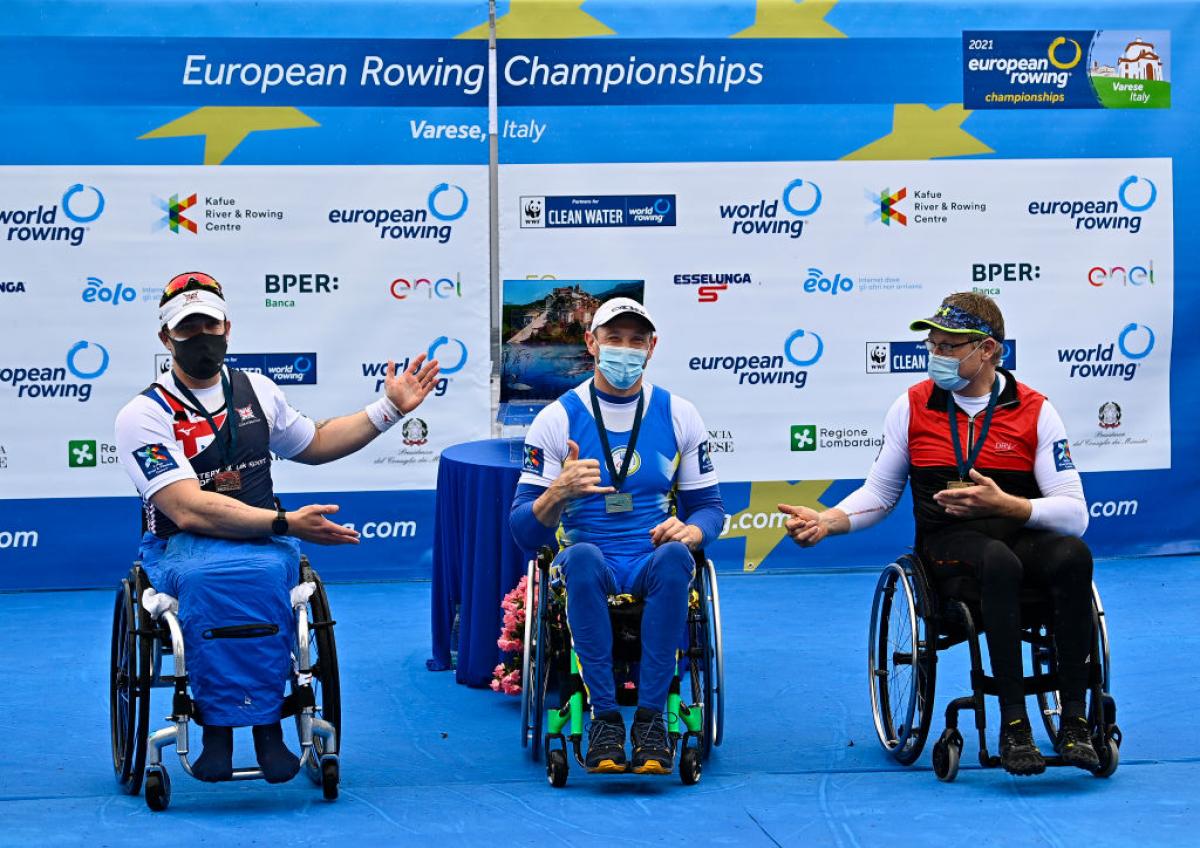 Three men in wheelchairs celebrating their medals