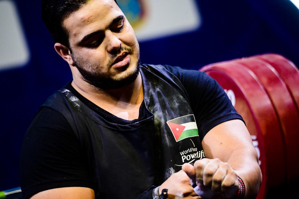 A man in a black shirt looking down to his arms