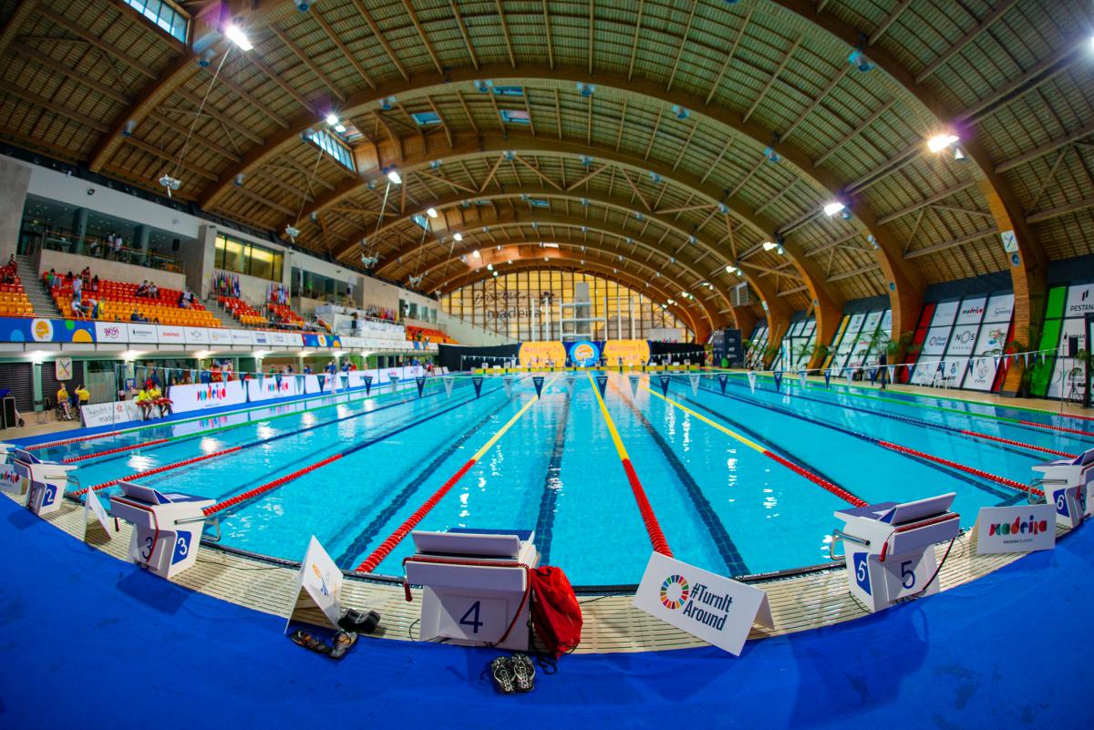 A indoor swimming pool with people watching in the stands