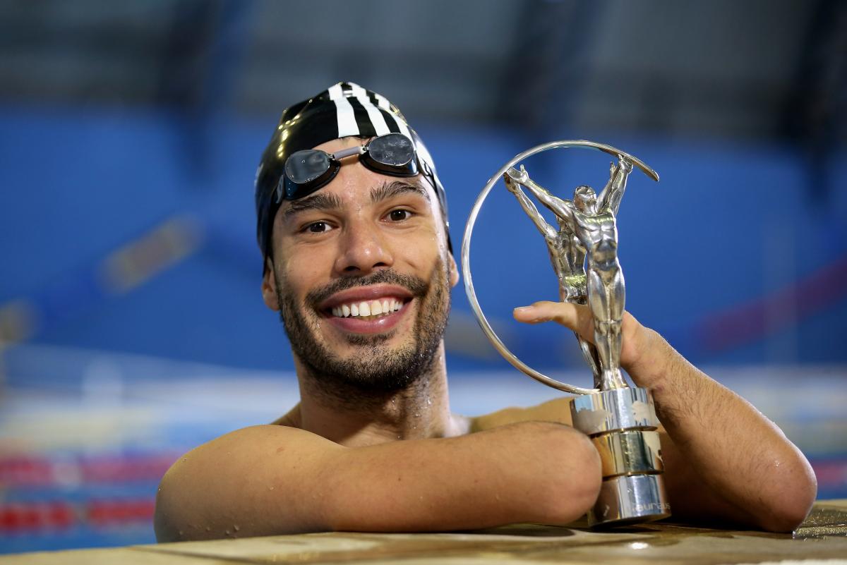 A man in a swimming pool posing with the Laureus Awards
