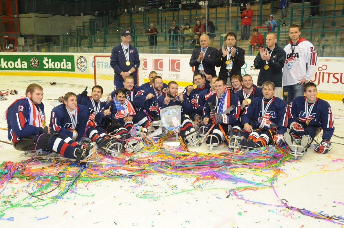 A group of Para ice hockey players with USA uniforms celebrating in an ice rink