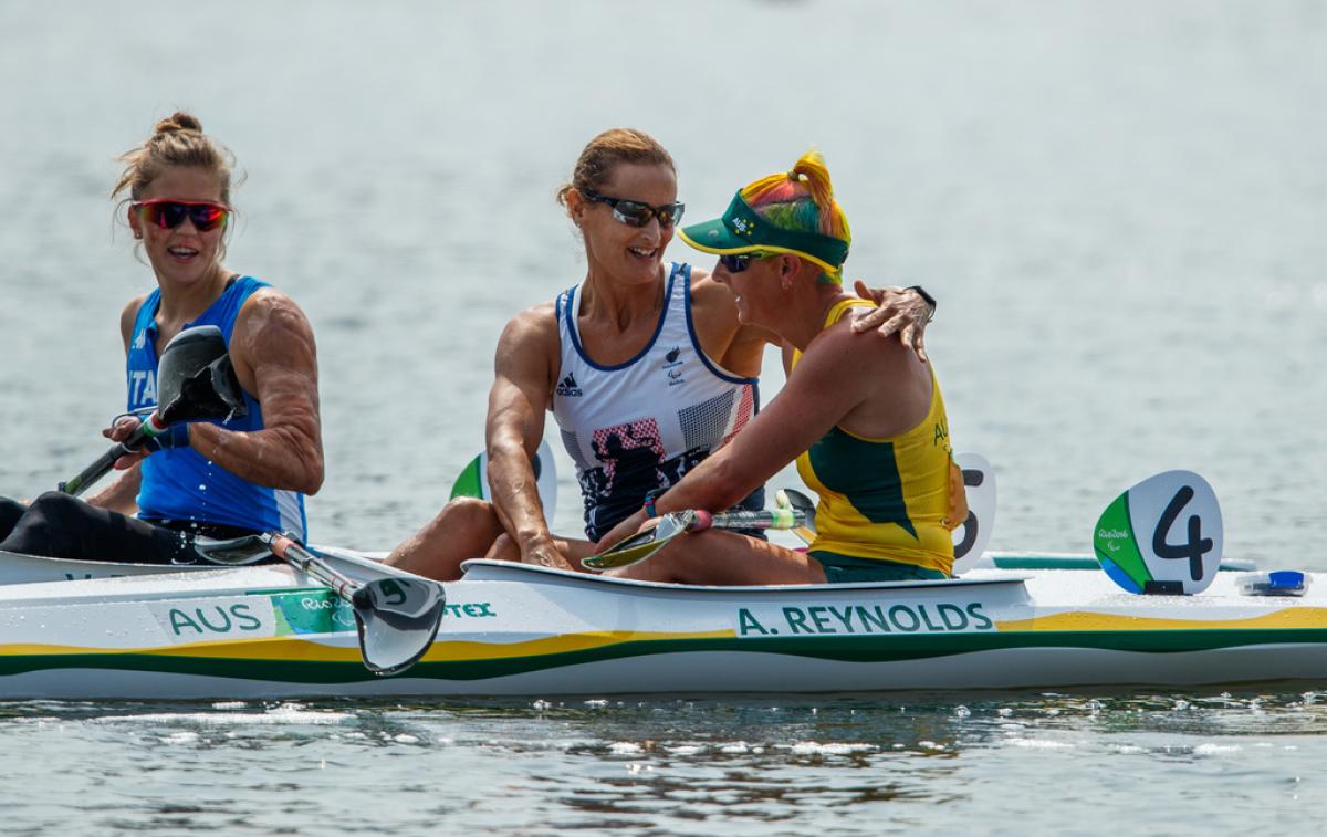 Two women in kayaks congratulate each other after a race
