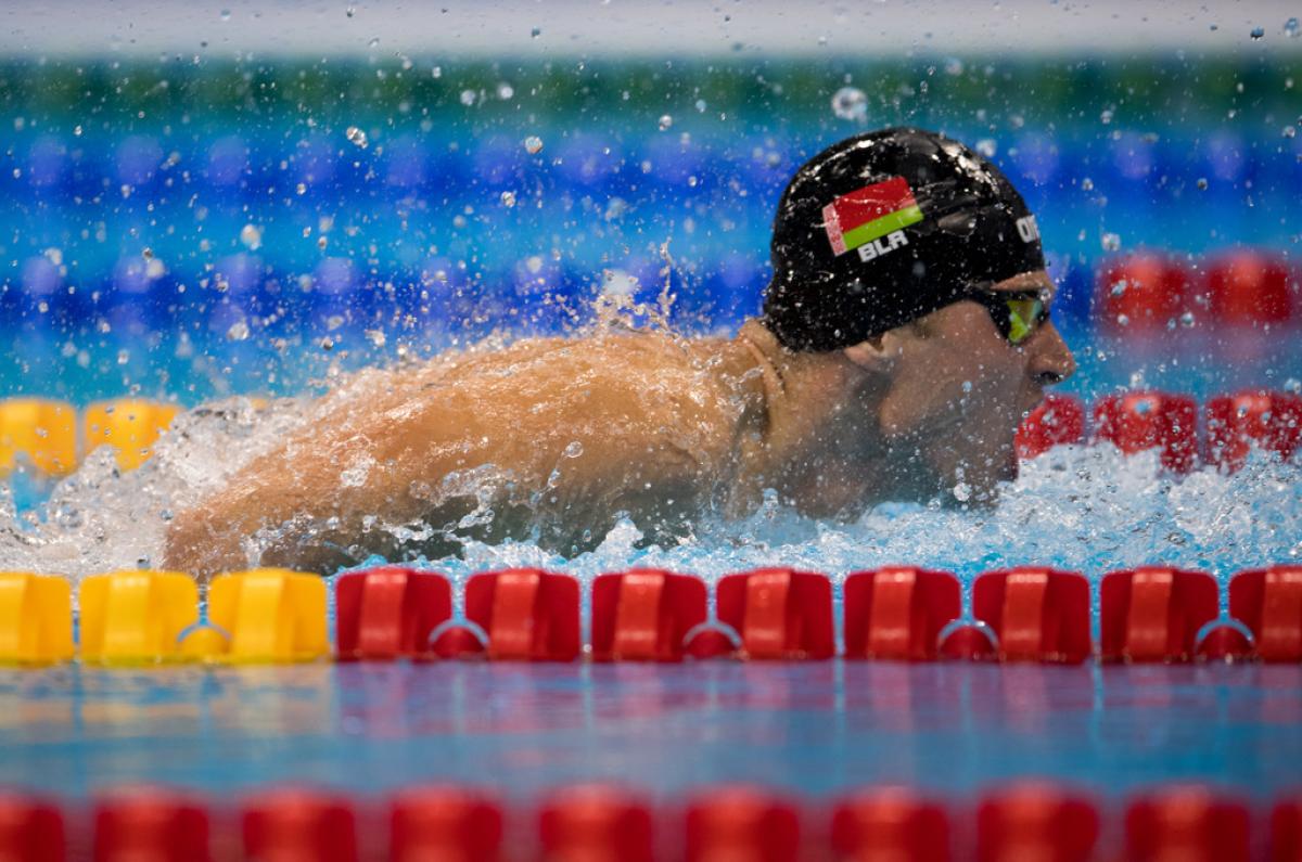 A man with a black cap swimming in a pool