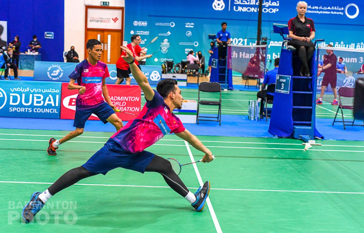 Male athlete reaches for the shuttle while competing in a males doubles team