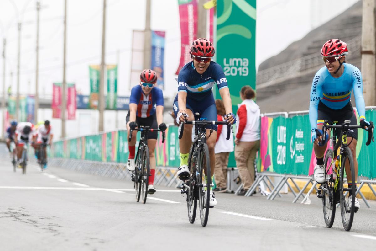 Argentine cyclists smiles after crossing the road race finish line first as Colombian cyclist who came second smiles to her