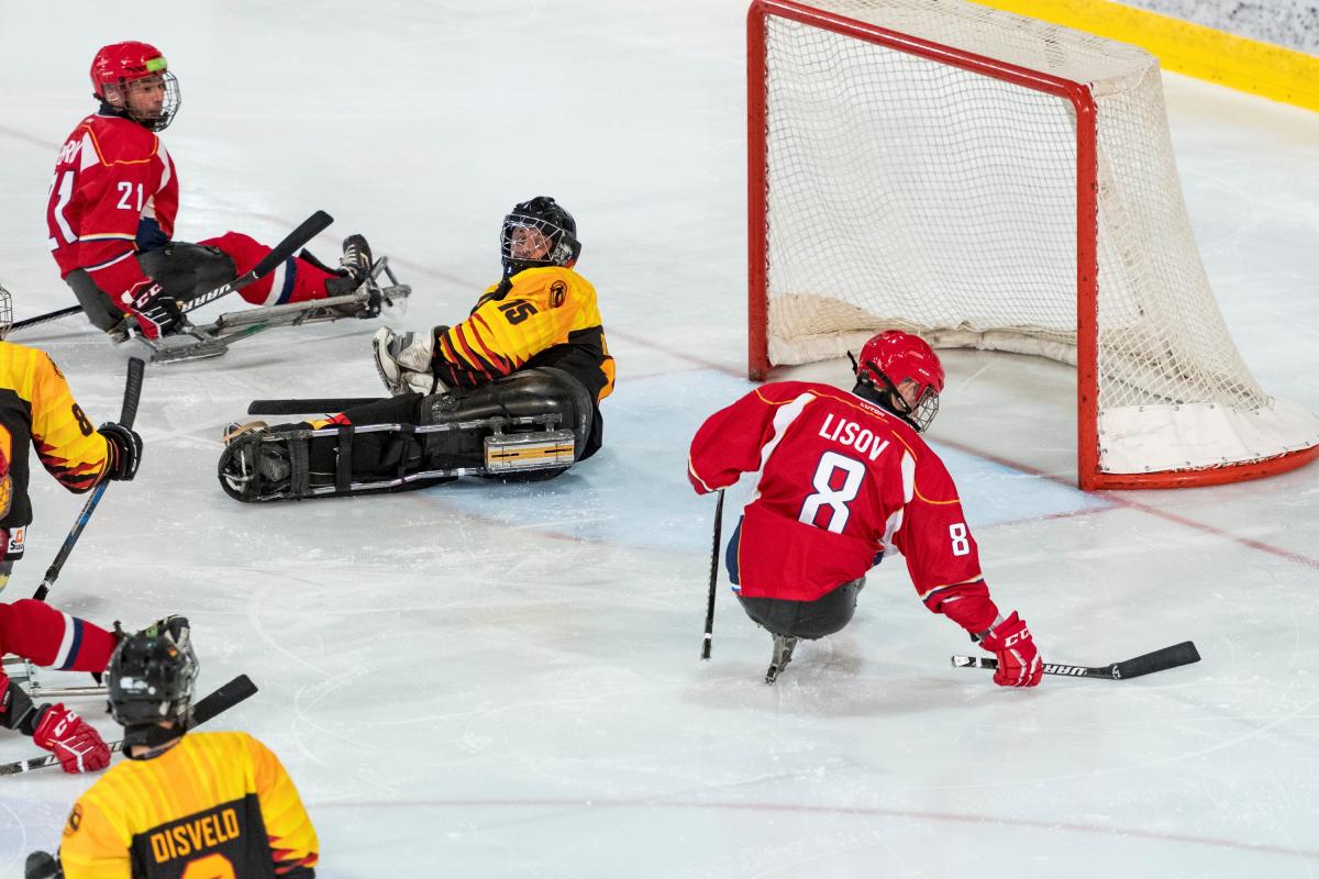 A Para ice hockey player scoring a goal observed by other four players
