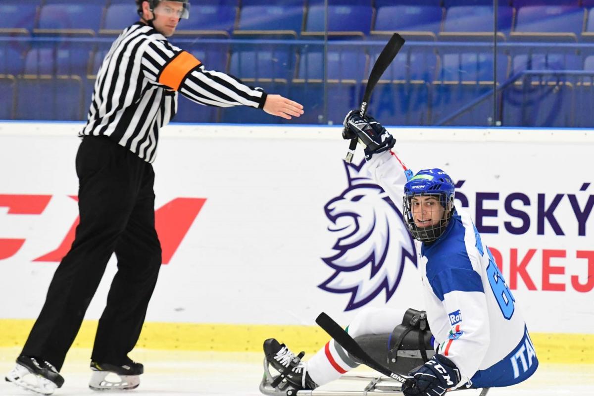 An ice hockey in sledges on an ice rink near a referee