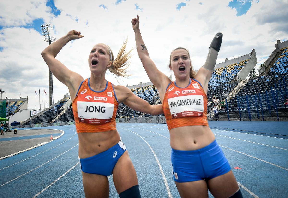 Two women with Netherlands uniform celebrating in a blue athletics track