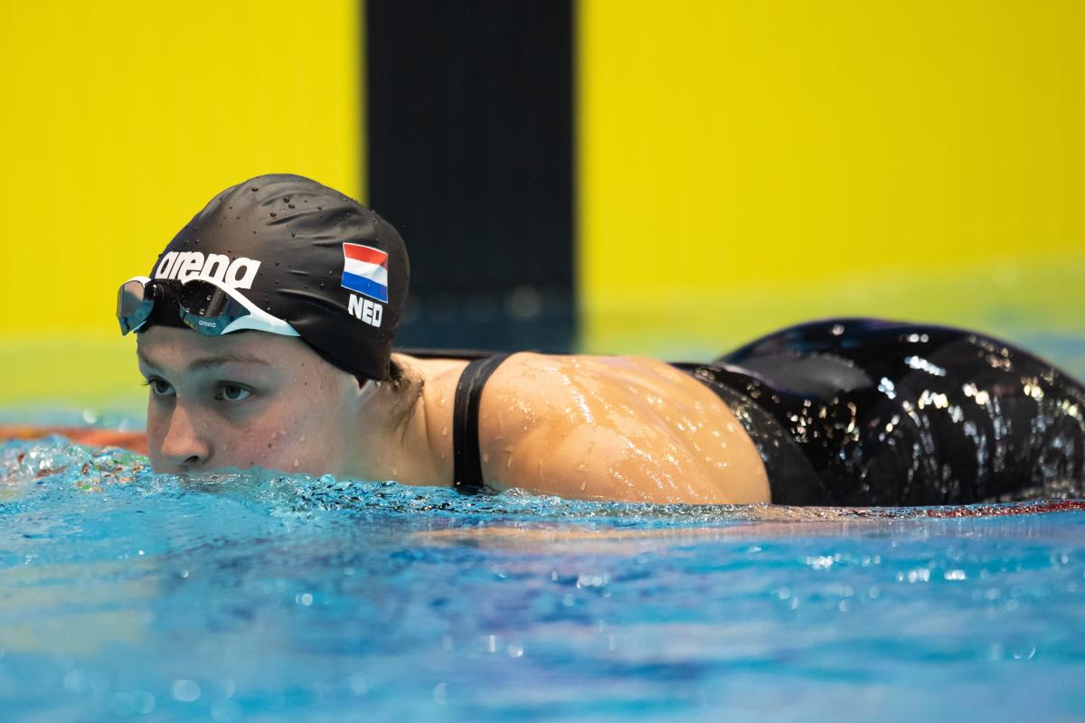 A woman with a black swimming cap putting her head out of the water