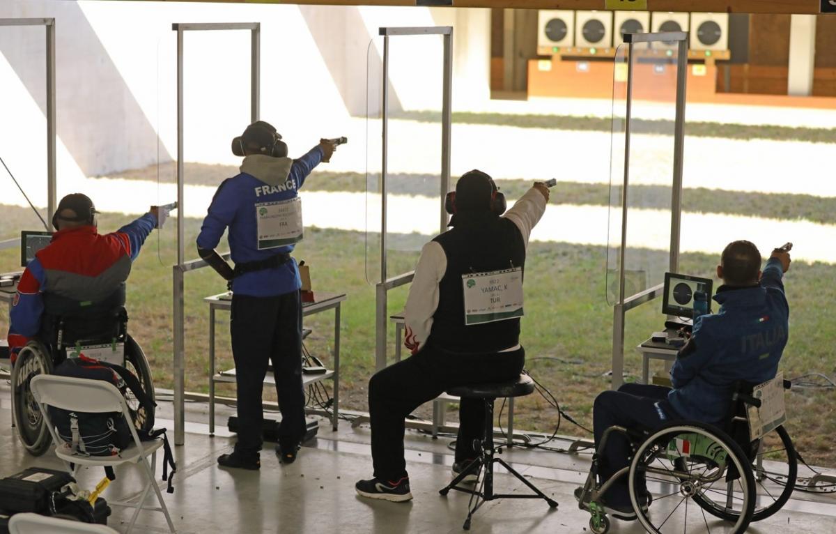 A group of four people competing with pistols in a shooting range