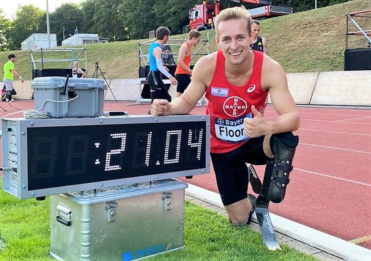 A male athlete with a prosthetic leg next to a score showing his world record