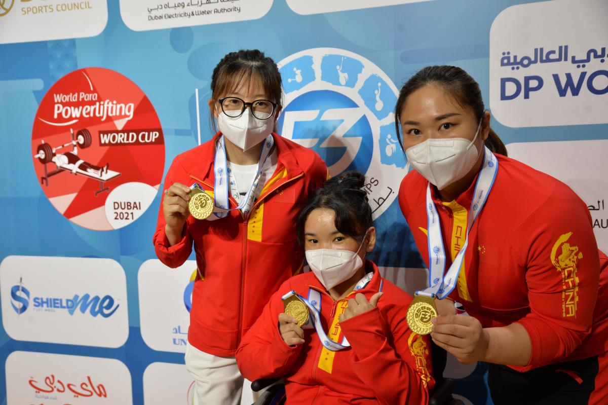 Three women with the uniform of China showing their gold medals