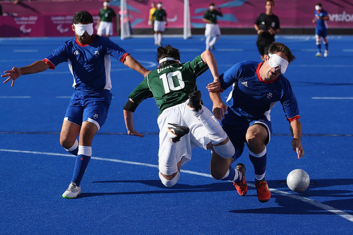 Two French defenders stop a Brazilian blind footballer