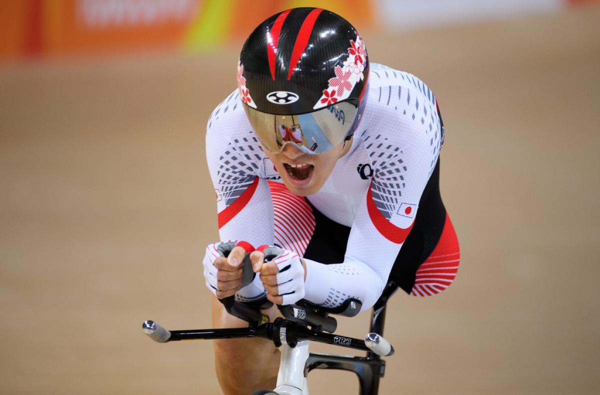 Cyclist with one leg wearing Japanese gear opens his mouth as he makes an effort during a sprint