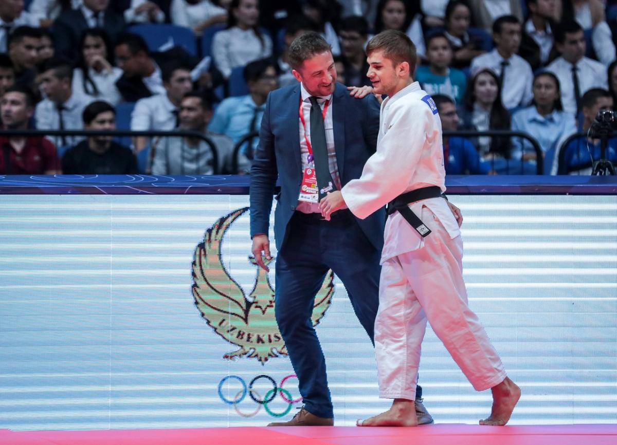 Judo coach guides blind judoka off the mat