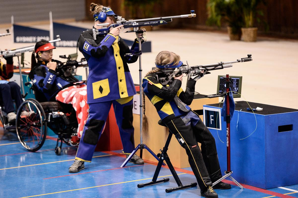 Three female athletes shooting a rifle in a range