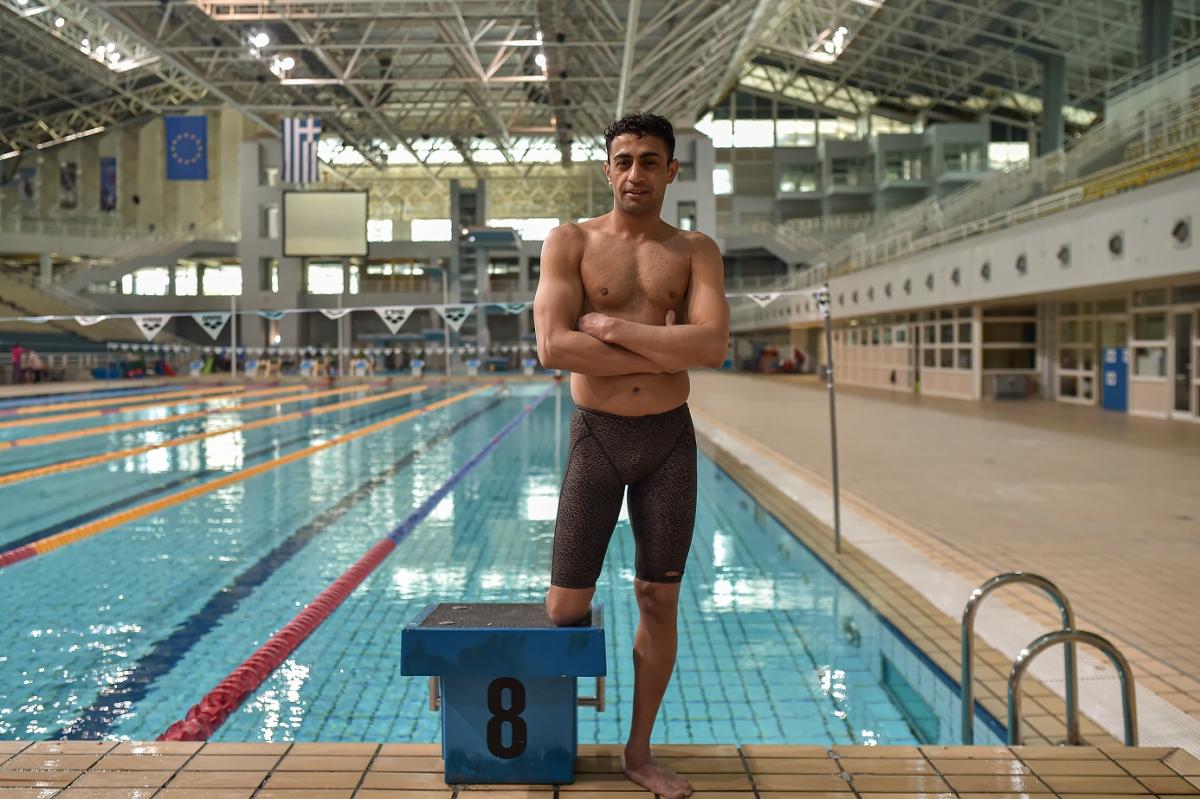 Swimmer Ibrahim Al Hussein posing in front of the pool while wearing his swimsuit