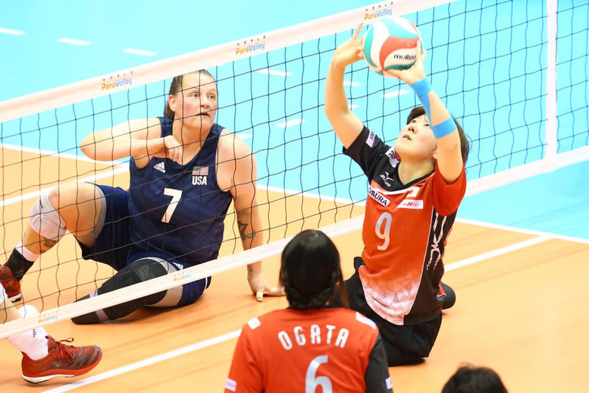 Chinese player sets the volleyball as USA opponent watches on the other side of the net