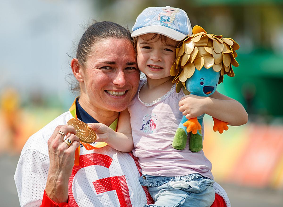 Sarah Storey cuddles her daughter and displays her gold medal