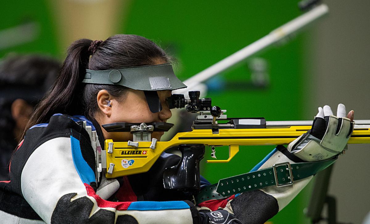 A woman shooting with a rifle in a competition