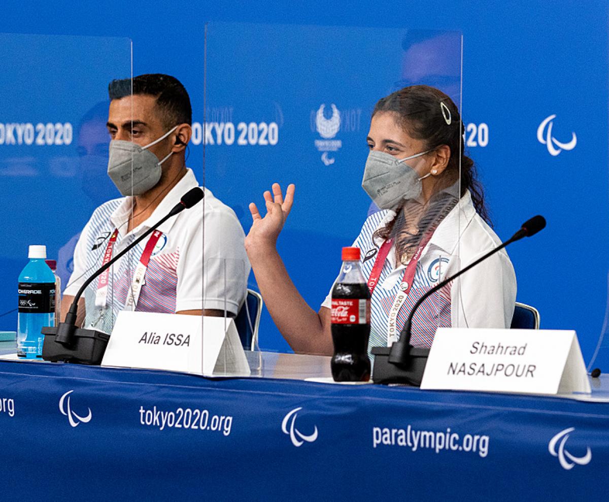 A man and a woman in a press conference wearing face masks