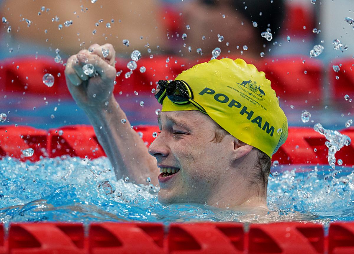 A man celebrating in the swimming pool with his fist high