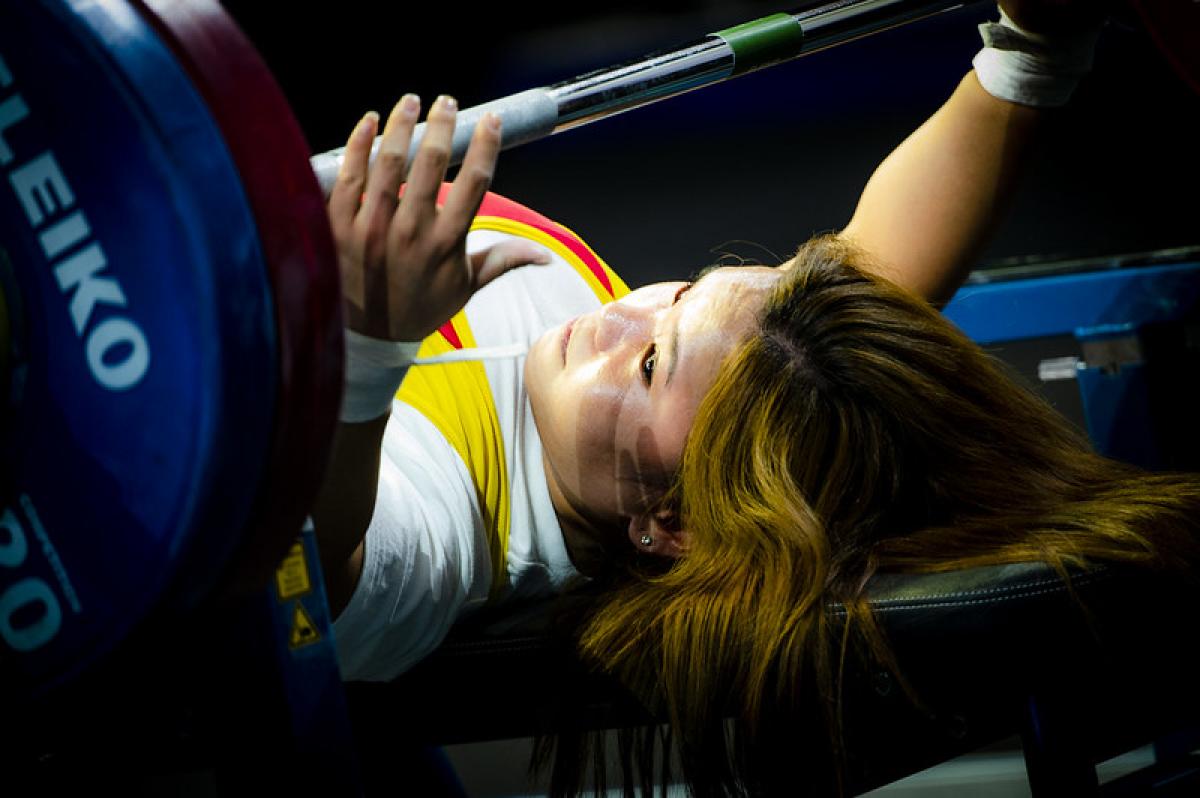 A woman putting her hands around a bar on a bench press