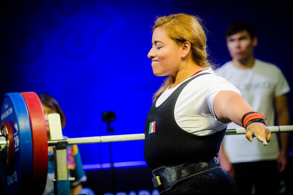 A woman stretching her arms in front of a bench press in a powerlifting competition