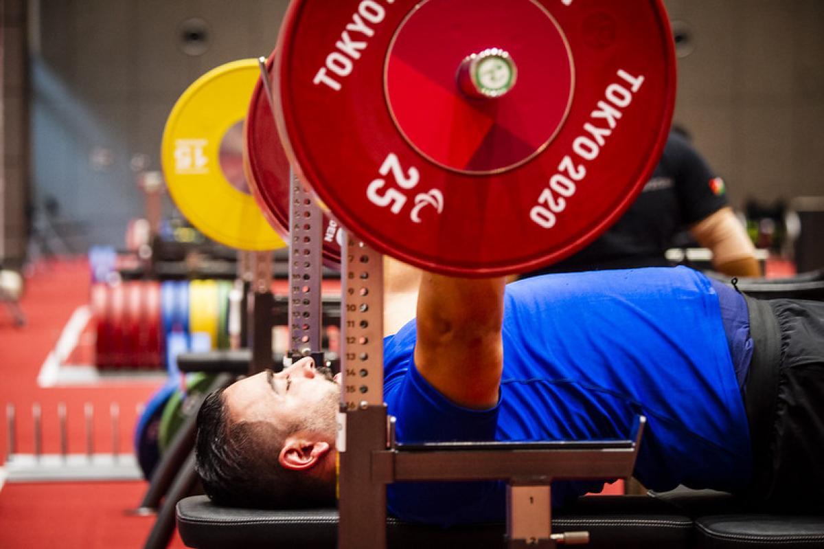 A man with a blue shirt practicing on a bench press