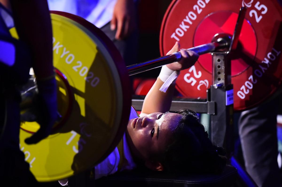 A woman preparing to lift the bar on a bench press competition