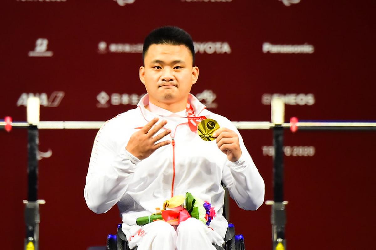 A man showing his medal and four fingers in a hand
