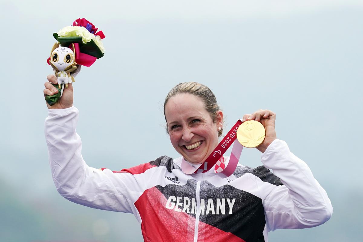German cyclist Annika Zeyen on the podium holding the gold medal with a smile from ear-to-ear