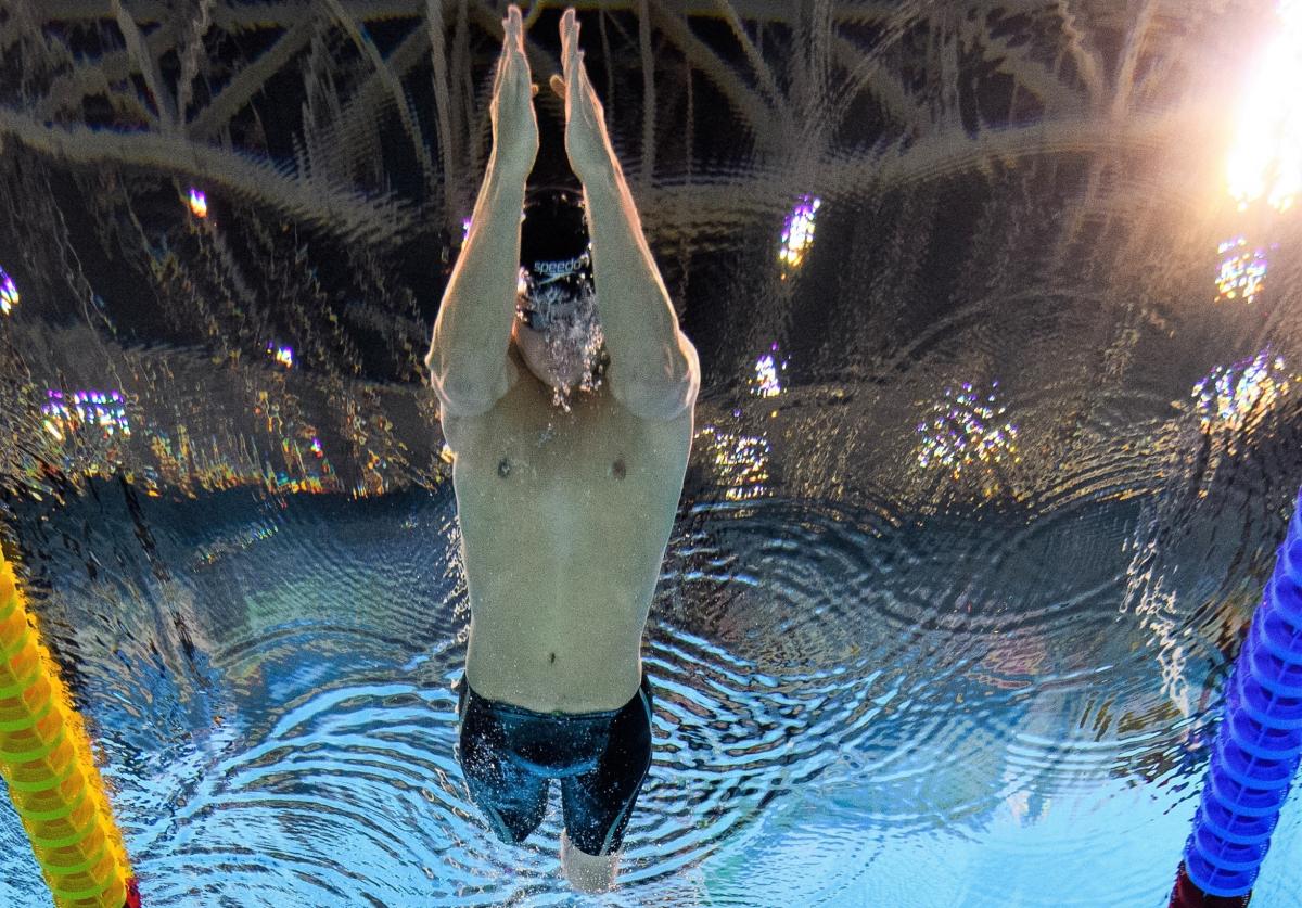 An underwater image of a man without legs swimming in a pool