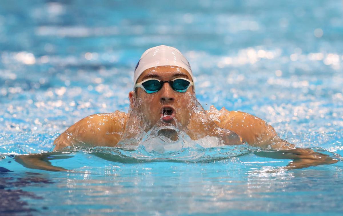 A man swims in the pool with the goggles and swimming cap