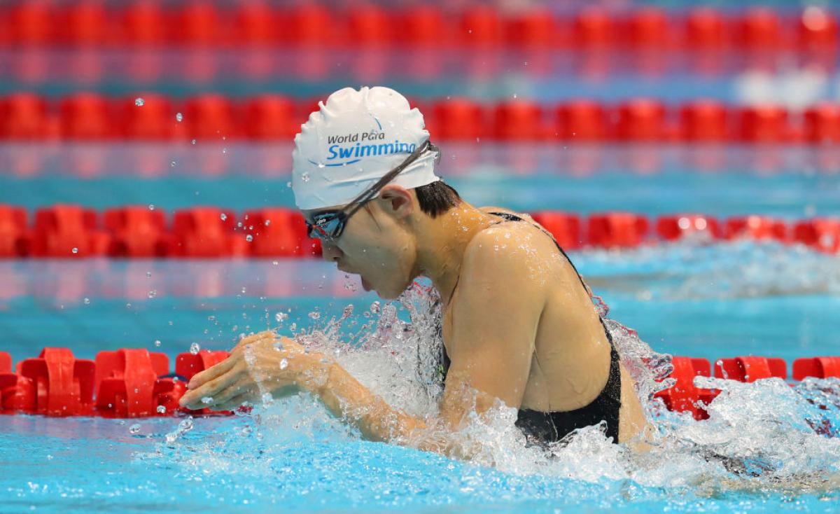 A female swimmer in the pool swimming in the breaststroke style