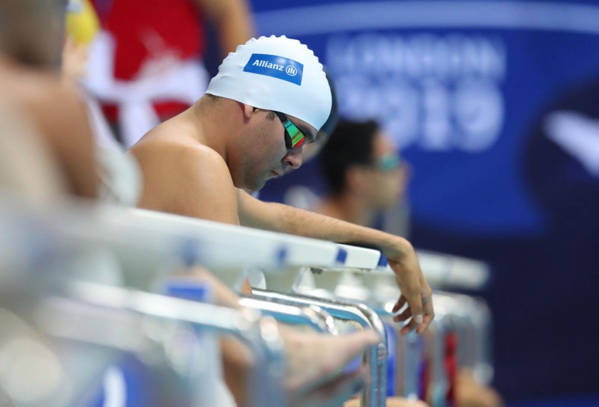 A man sits on the edge of the pool waiting for his race to start