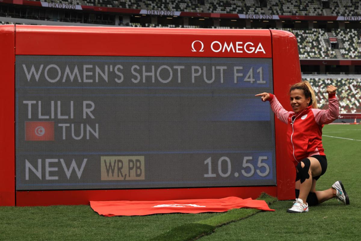 A woman pointing at a screen showing her world record mark in a stadium