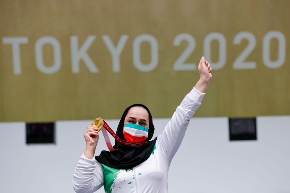 A woman celebrating with her gold medal in front a Tokyo 2020 banner