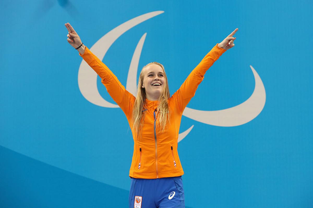 A woman with two raised hands, smiling on the podium