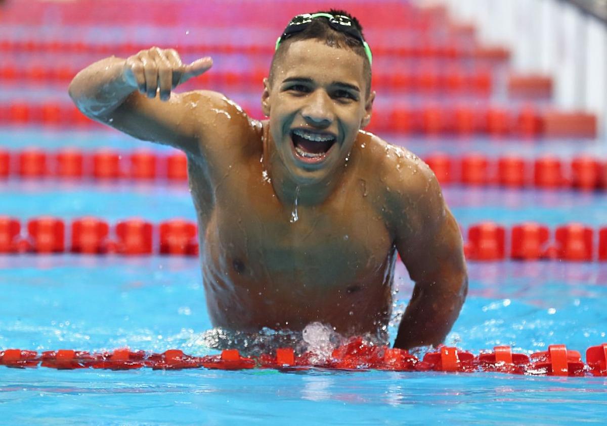 A man in the pool smiles with a thumbs up