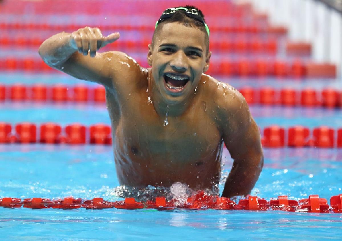 A man in the pool smiles with a thumbs up 