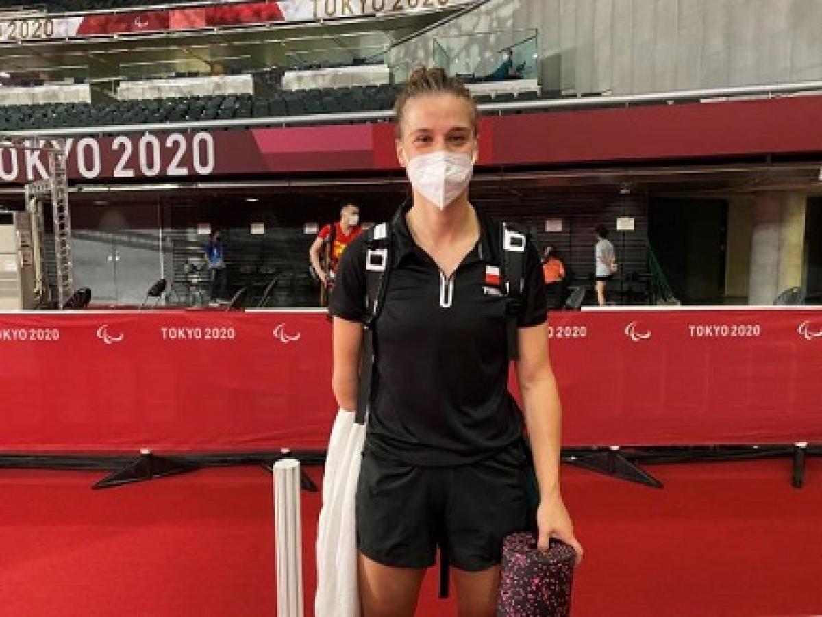 Wearing a white mask and black top and shorts, Natalia Partyka smiles in the press mixed zone