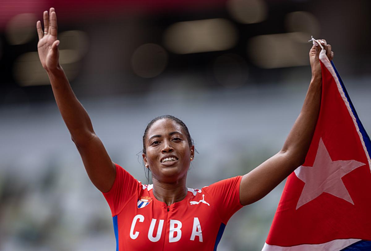 Cuban sprinter Omara Durand holds her coutry's flag and smiles after winning her sixth Paralympic gold