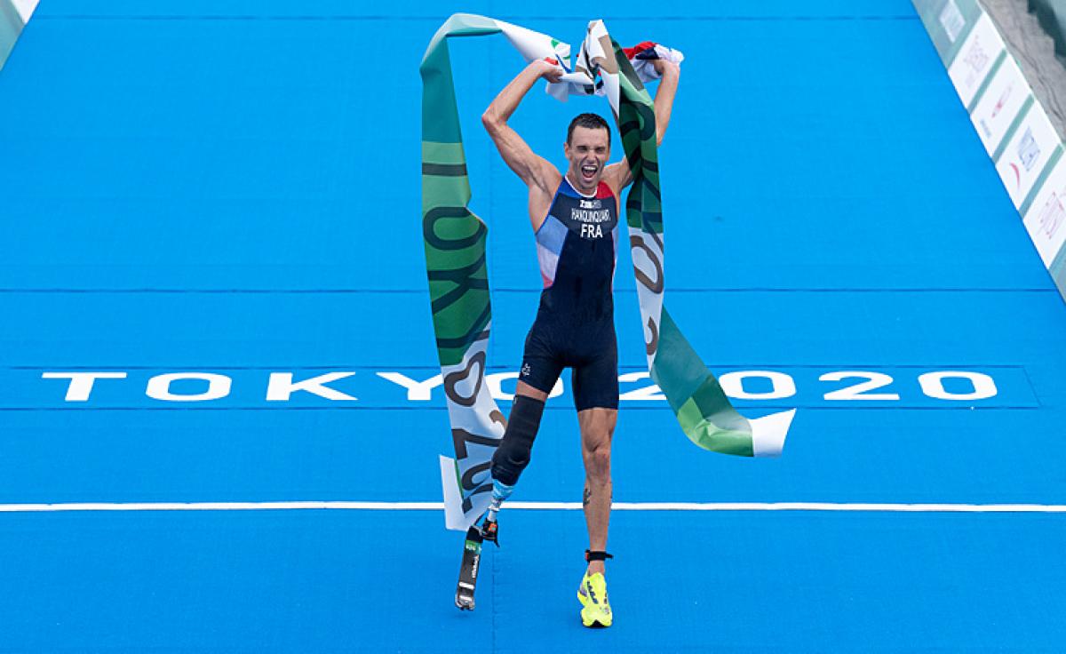 Male triathlete celebrates crossing finish tape