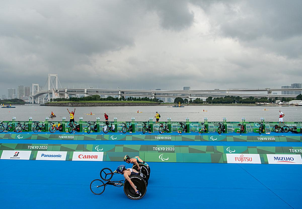 Two wheelchair racers neck-in-neck down home stretch