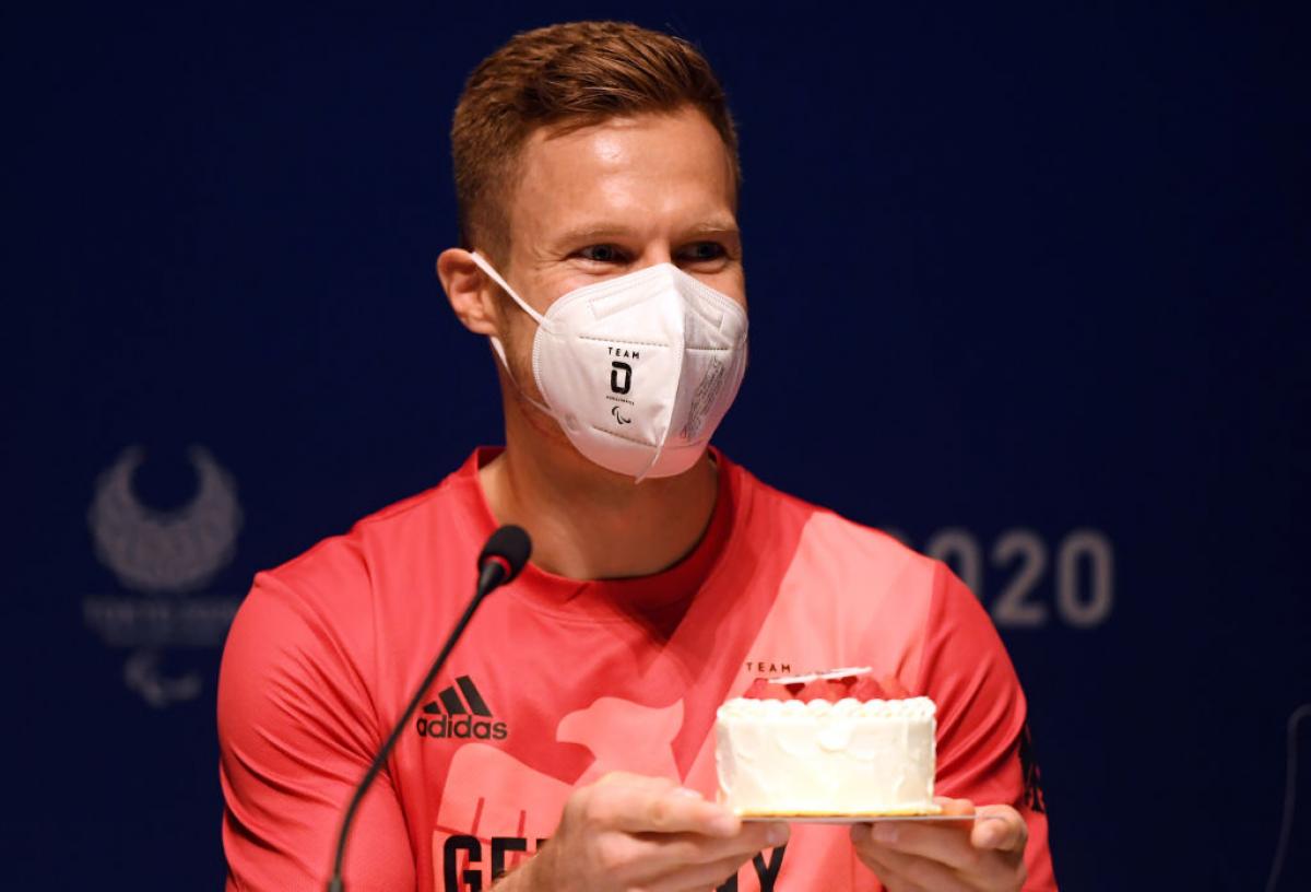 Man with mask on accepts birthday cake
