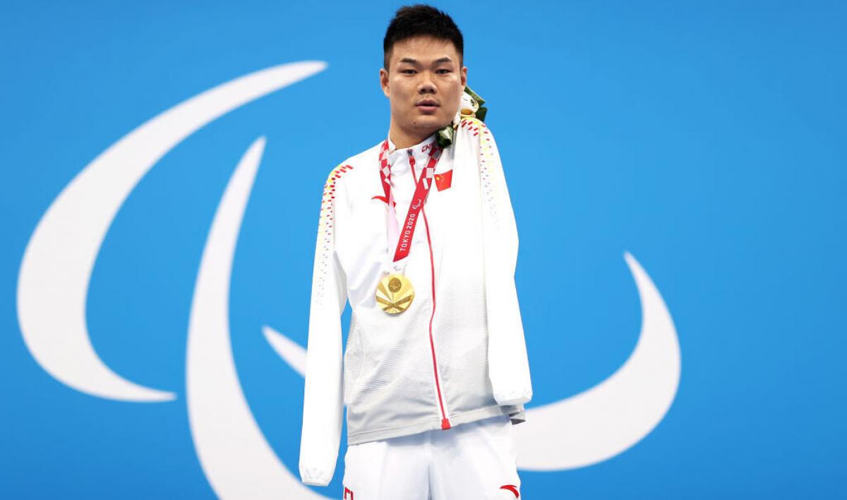 A man poses with a gold medal around his neck